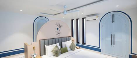 A modern hotel room with a large bed, a nightstand, a ceiling fan, and a wardrobe.