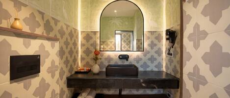 A bathroom with patterned walls, a mirror, a sink, a towel rack, and a shelf with a vase.