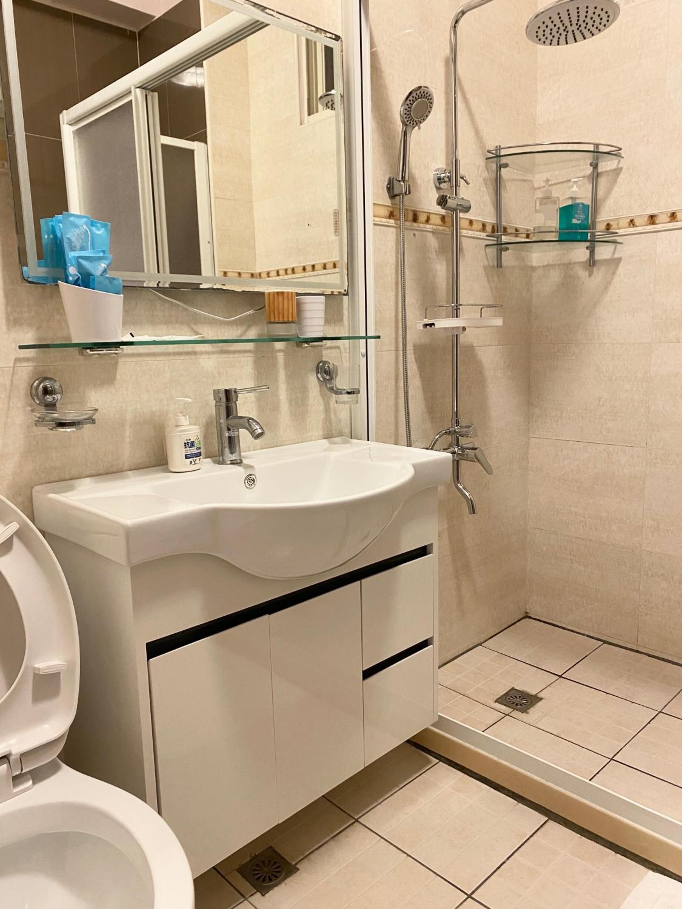 A modern bathroom with a white sink, mirror, and shower.