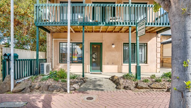 A two-story building with a balcony, a gated entrance, and a brick pathway leading to the door. - Main Street of Goolwa - WIFI, Smart TV, Linen included (Goolwa)