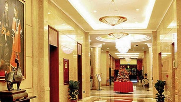 Un hall d’hôtel avec un sol en marbre, un lustre et un comptoir d’accueil.