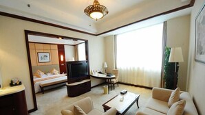 Une chambre d’hôtel équipée d’un lit, d’une télévision, d’un canapé, d’une table basse et d’un bureau.