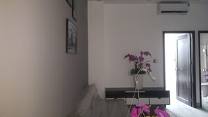Une chambre comprenant un lit, une table de chevet, une orchidée en pot et une porte donnant sur une salle de bain.