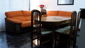 A dining area with a round table, four chairs, and an orange sofa. - Charming 3 bedroom apartment centrally located (Cullera)