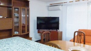 A living room with a television, wooden cabinet, dining table, and chairs. - Charming 3 bedroom apartment centrally located (Cullera)