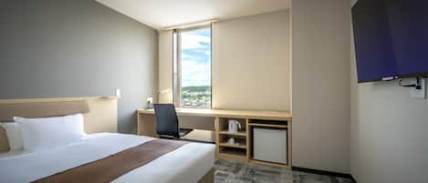 Una habitación de hotel con cama, escritorio, silla y televisor.