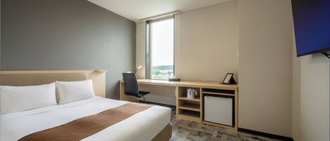 Ein Hotelzimmer mit einem großen Bett, einem Schreibtisch, einem Stuhl, einer kleinen Kommode und einem großen Fenster.