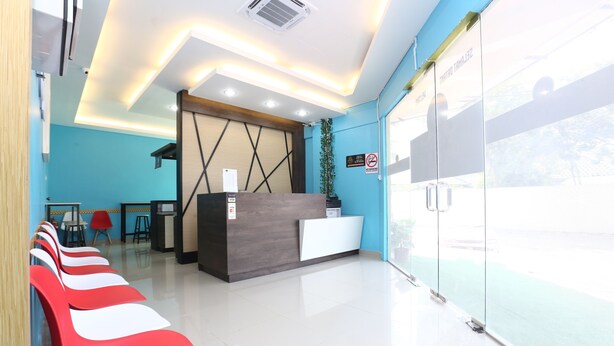 A reception area with a modern design, featuring a reception desk, seating area, and a large window offering a view. - Super OYO 89771 Dane & Shue (Kota Bharu)