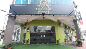 The exterior of the Dané & Shue Hotel with a modern design, featuring a large glass entrance and potted plants. - Super OYO 89771 Dane & Shue (Kota Bharu)