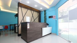 A reception desk with a dark wood finish, a white counter, and a blue wall. There is a 'Welcome' sign and a 'No Smoking' sign on the wall. - Super OYO 89771 Dane & Shue (Kota Bharu)