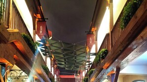 A narrow stone-paved alleyway with wooden structures on either side, overhead wooden beams, and hanging lanterns. - Huaqi Kaiserdom Hotel (Qingdao)