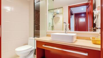 A modern bathroom with a toilet, shower, and sink.