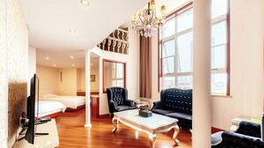 A hotel room with a bed, a sofa, a coffee table, a TV, and a chandelier. - Huaqi Kaiserdom Hotel (Qingdao)