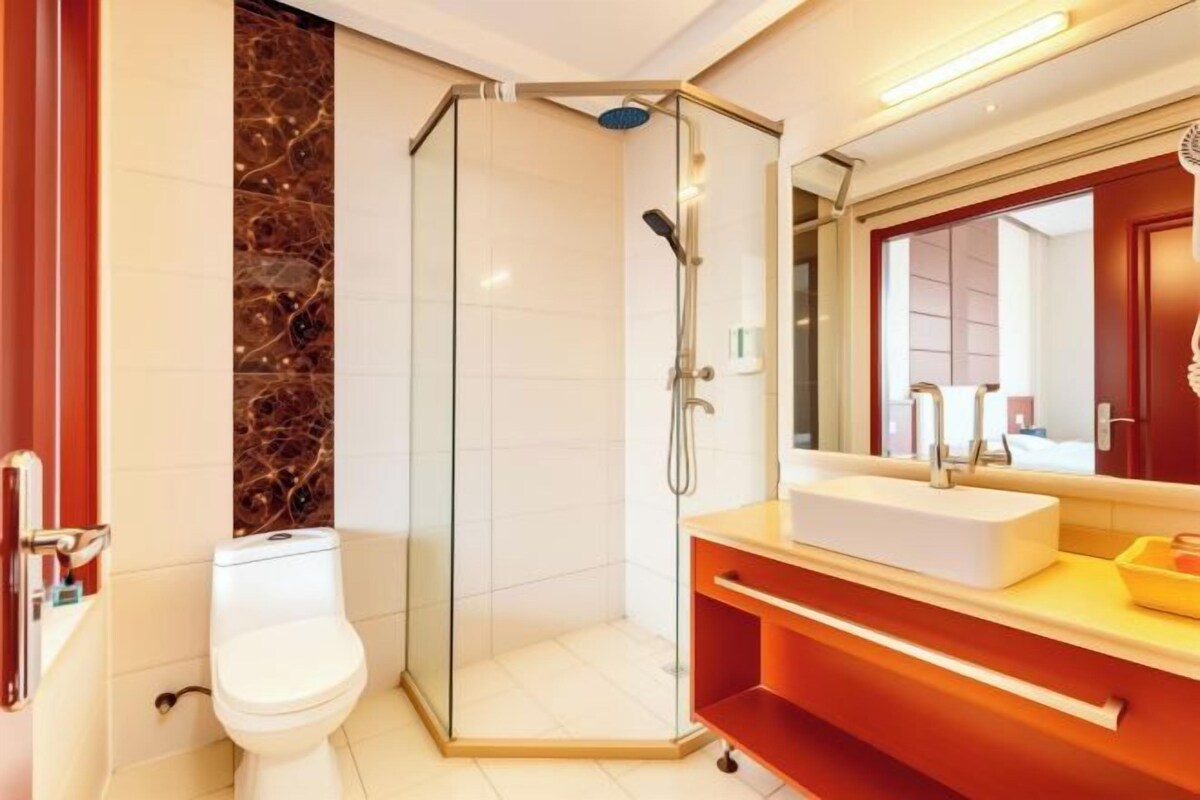 A modern bathroom with a glass-enclosed shower, a white toilet, and a vanity with a mirror.