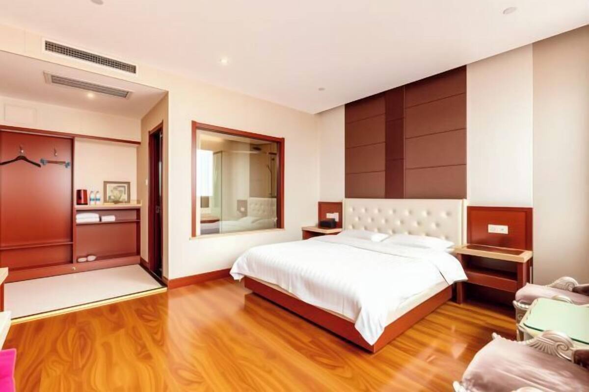 A bedroom with a large bed, a wardrobe, a mirror, and a bedside table.