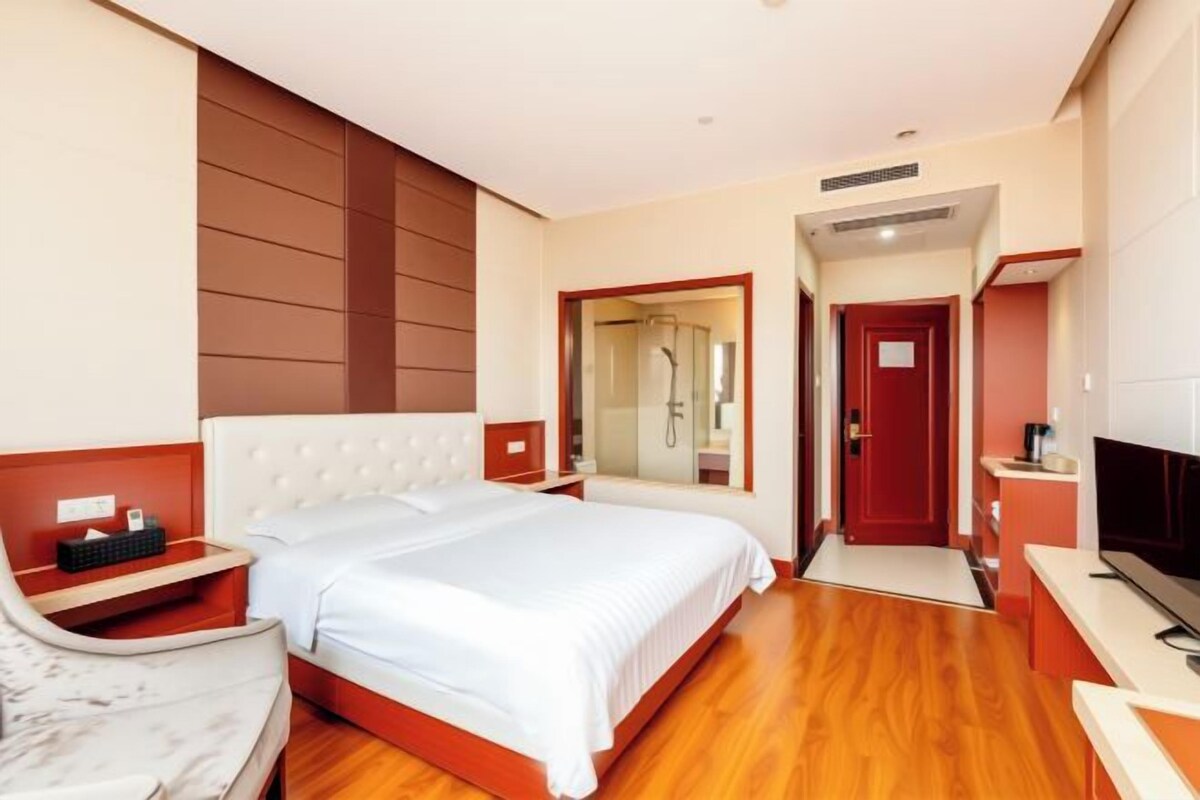 A hotel room with a bed, a TV, a desk, a chair, and a mirror.