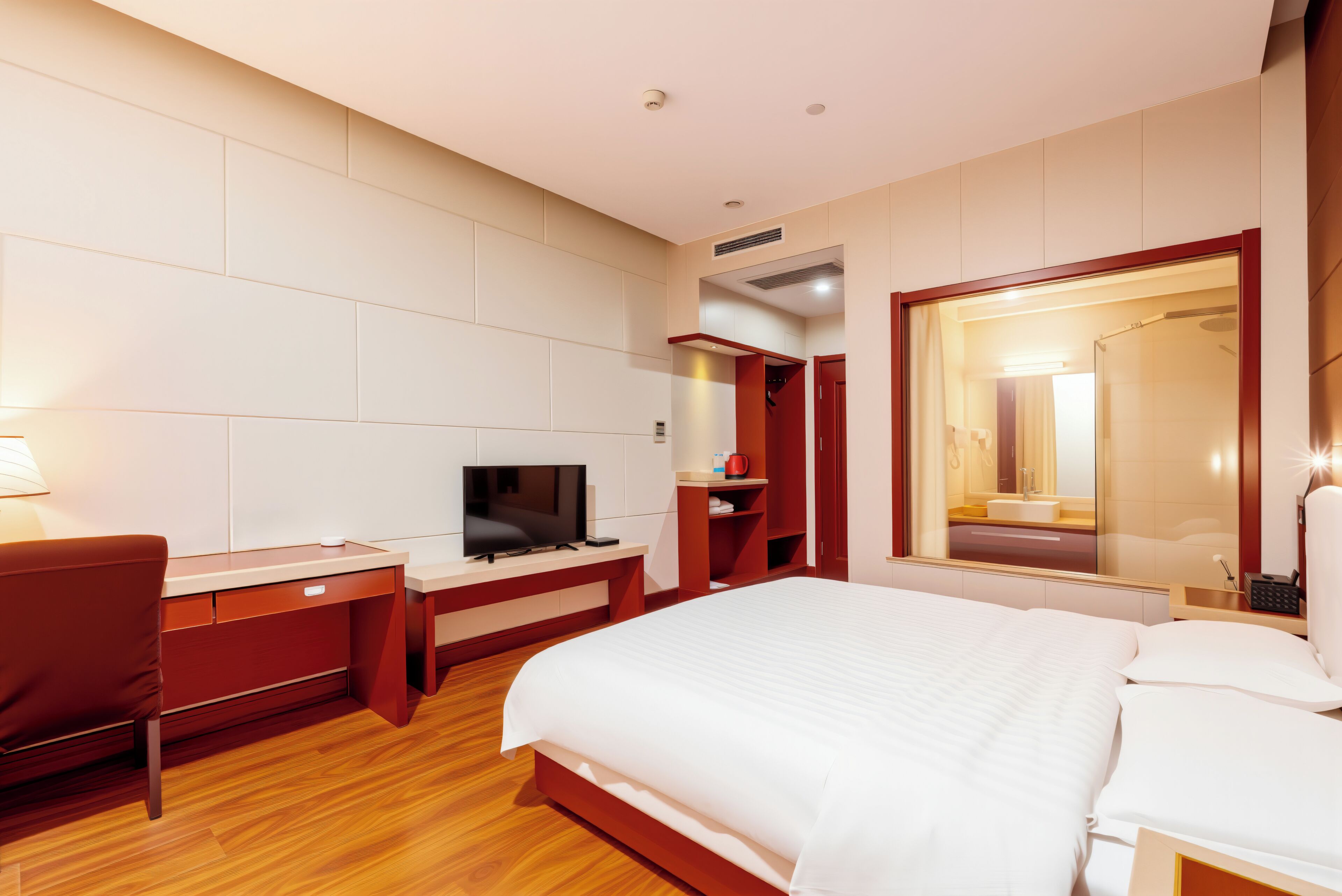 A hotel room with a bed, desk, television, and a mirror.