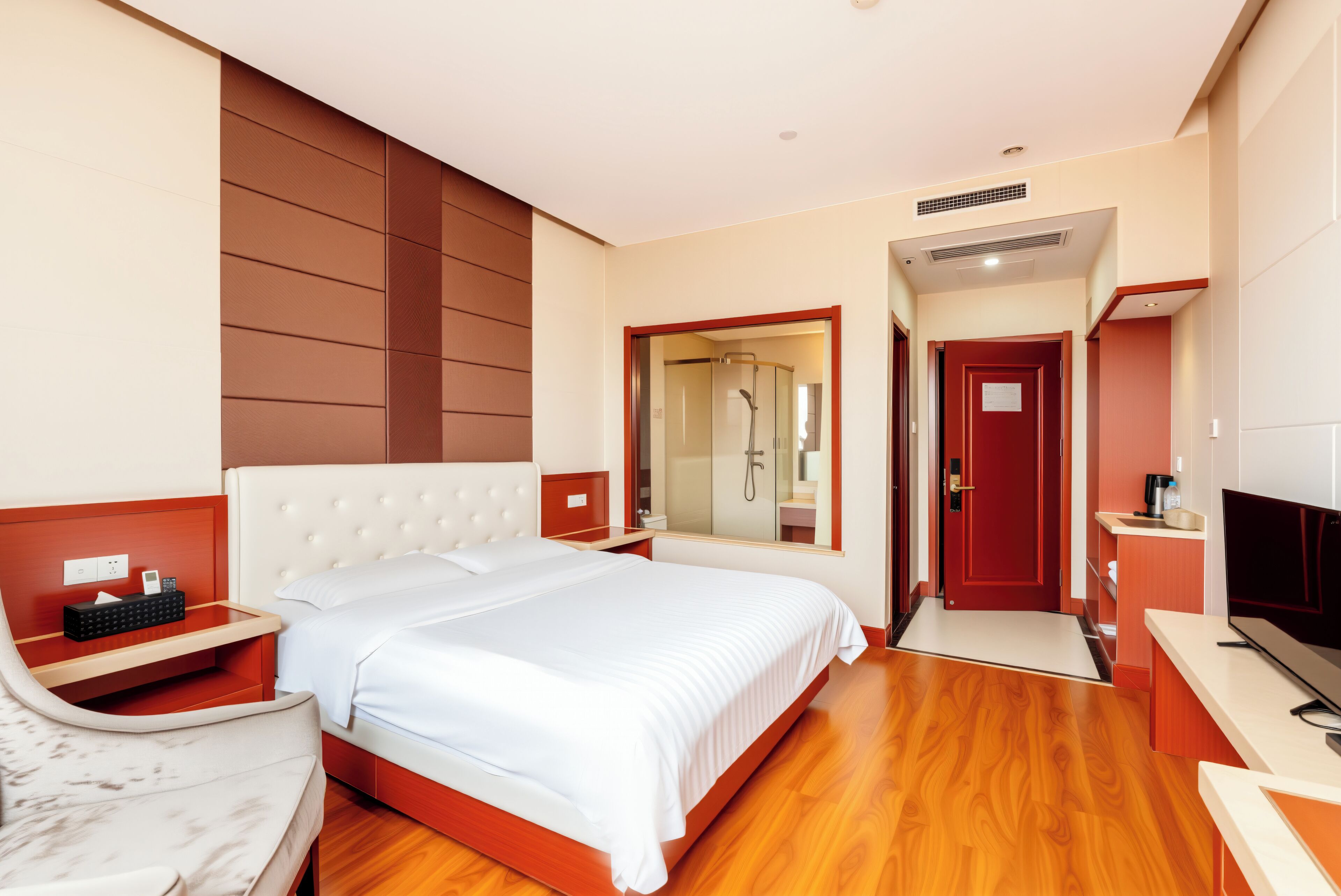 Une chambre d’hôtel avec un grand lit, une télévision, un bureau et une salle de bain avec douche.