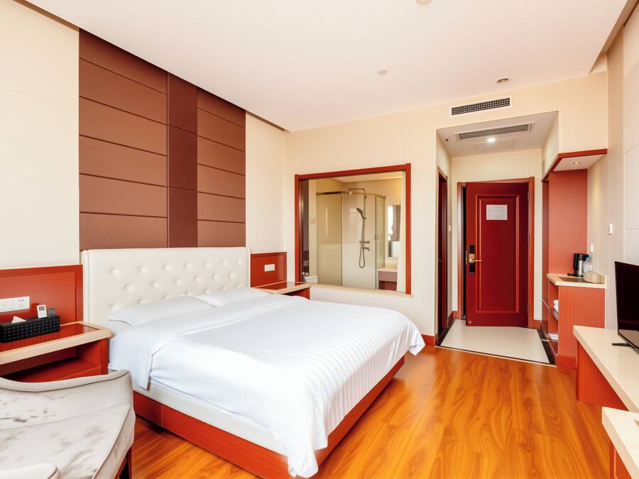 Une chambre d’hôtel avec un grand lit, une télévision, un bureau et une salle de bain avec douche.