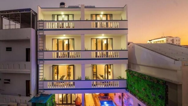 A multi-story hotel with balconies, a rooftop pool, and a green wall. - Calla Hotel Hoi an (Da Nang)