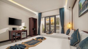 A hotel room with a bed, a desk with a TV, a wardrobe, and a view of the outdoors. - Calla Hotel Hoi an (Da Nang)