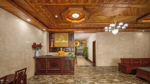 A lobby with a reception desk, wooden furniture, and a marble floor. - Calla Hotel Hoi an (Da Nang)