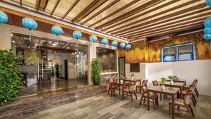 A restaurant with wooden ceiling beams, blue hanging lanterns, and a tiled floor. - Calla Hotel Hoi an (Da Nang)