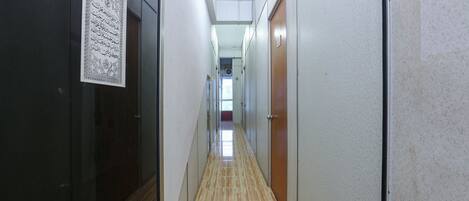 A hallway with doors on both sides, a tiled floor, and a ceiling with recessed lighting.