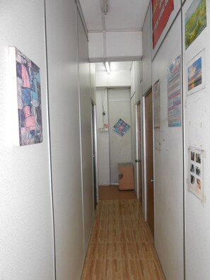 A narrow hallway with a wooden floor, white walls, and various posters and notices. - OYO 89755 D&d Budget Inn (Kota Bharu)
