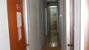 A corridor with doors on both sides, a wooden floor, and a sign on the left door. - OYO 89755 D&d Budget Inn (Kota Bharu)