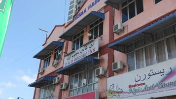 A multi-story building with various commercial establishments on the ground floor, including a budget inn and a cosmetic shop.