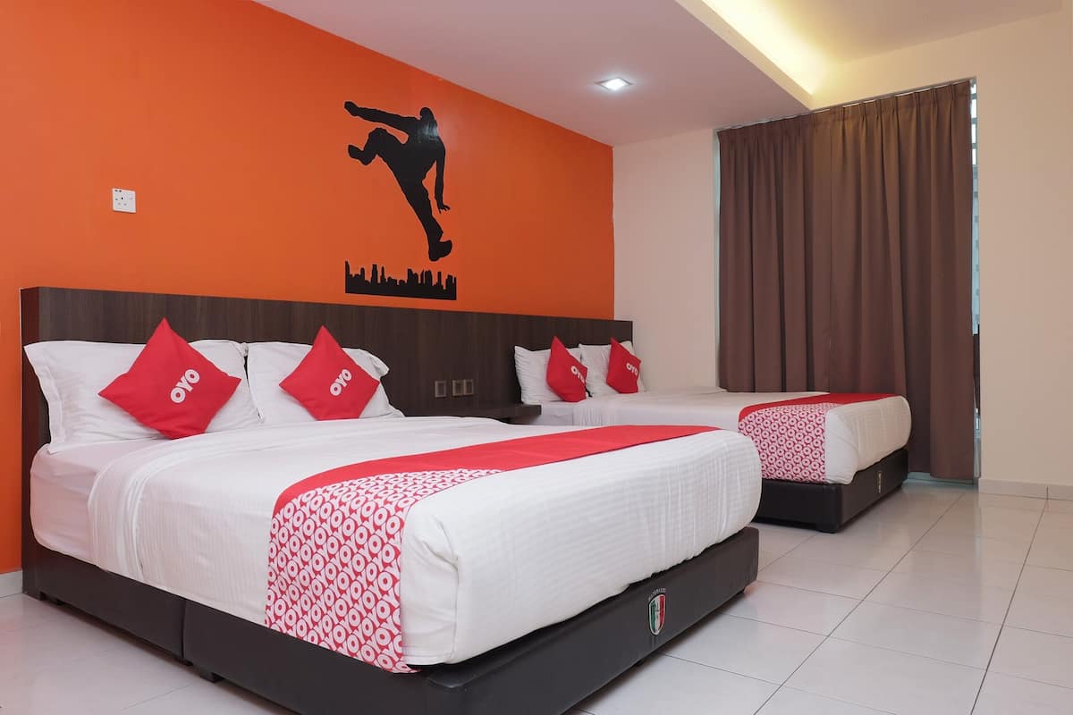 Habitación de hotel con dos camas, cada una con ropa de cama blanca y almohadas rojas, un mural de un horizonte urbano en la pared y cortinas marrones.