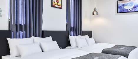 Ein Hotelzimmer mit zwei Betten, dunklen Vorhängen, einem Gemälde an der Wand und einer Hängelampe.