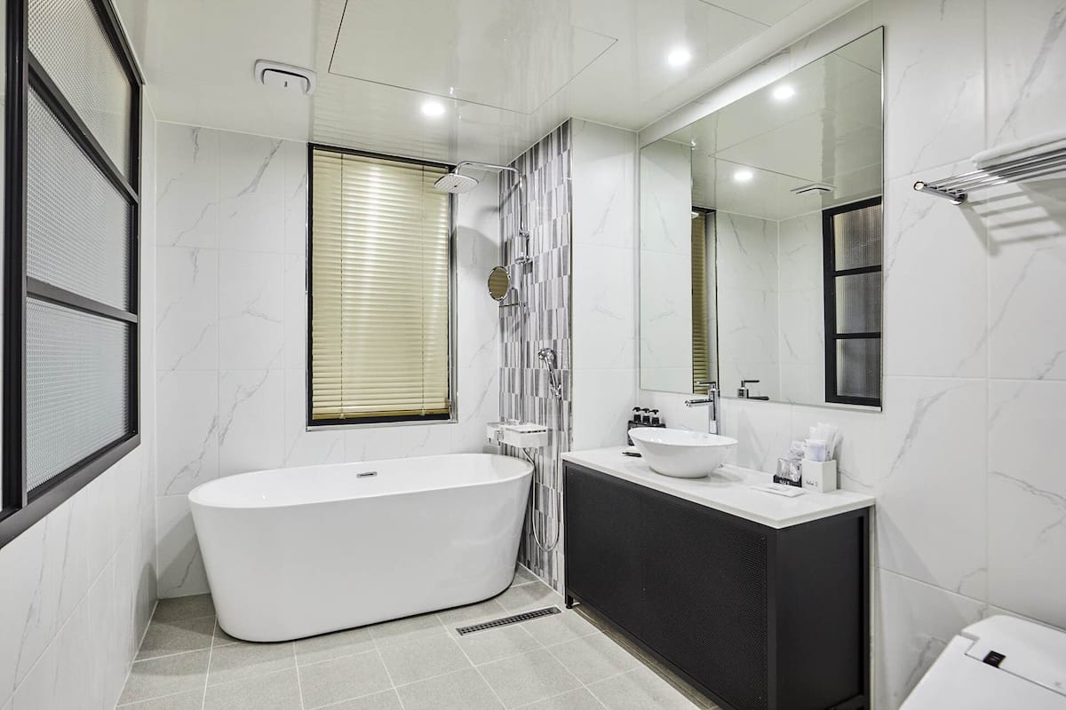 A modern bathroom with a freestanding bathtub, a large mirror, and a vanity with a sink.