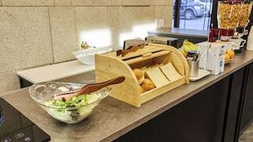 Una barra de desayuno con pan, mantequilla y un bol de ensalada.