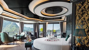 A luxurious bedroom with a large bed, a massage chair, a view of the mountains, and a balcony with outdoor seating. - Rita Cruise (Tuan Chau)