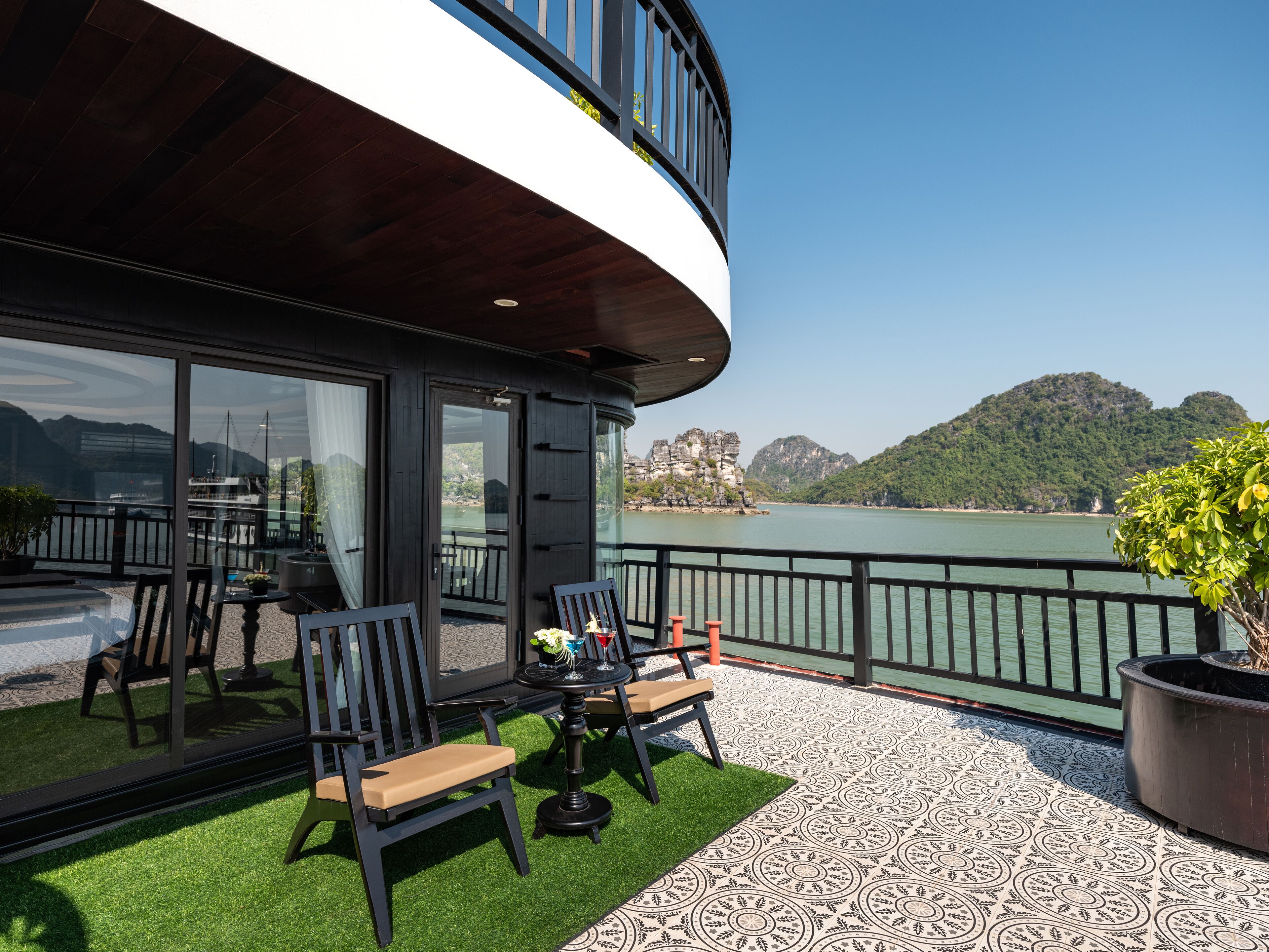 Een balkon met een tafel en stoelen, met uitzicht op een waterpartij en heuvels.