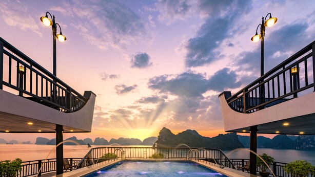 A swimming pool with a sunset view, surrounded by railings and potted plants. - Rita Cruise (Tuan Chau)