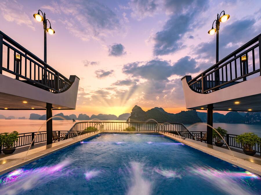 Una piscina con vistas a la puesta de sol, rodeada de barandillas y plantas en macetas.