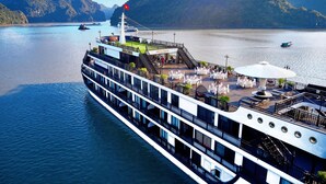 A river cruise ship with multiple decks, outdoor dining areas, and a flag. - Rita Cruise (Tuan Chau)