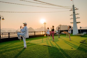 Un grupo de personas practicando yoga en una terraza con vistas panorámicas a montañas.