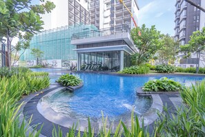 A modern building with a glass facade, a rooftop terrace, and a surrounding landscaped area with a pool. - OYO Home 89612 Studio Midhill Genting (Genting Highlands)