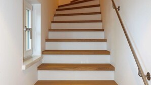 A staircase with wooden steps and a handrail, leading to a landing with a door and a window. - Bodenschneid Suites Neureuthblick - Bodenschneid Suite Neureuthblick (Kreuth)