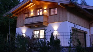 A two-story wooden house with a balcony, large windows, and a garage. - Bodenschneid Suites Neureuthblick - Bodenschneid Suite Neureuthblick (Kreuth)