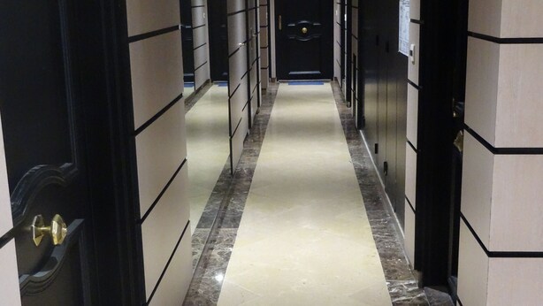 A hallway with a marble floor, black and beige walls, and doors on both sides. - One-Bedroom Apartment, good standard, quiet with parking (Lyon)