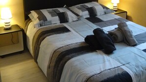 A neatly made bed with a striped blanket, two bedside lamps, a nightstand, and a framed picture on the wall. - One-Bedroom Apartment, good standard, quiet with parking (Lyon)