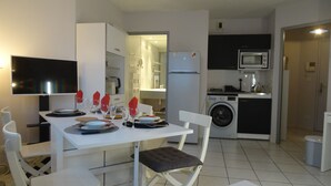 A compact kitchen with a washing machine, a microwave, and a refrigerator. - One-Bedroom Apartment, good standard, quiet with parking (Lyon)