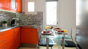 Una cocina moderna con armarios color naranja, una mesa de comedor de vidrio y alimentos para el desayuno.