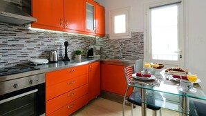 Una cocina moderna con gabinetes naranjas, una mesa de comedor de vidrio y alimentos para el desayuno.