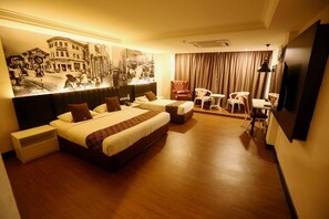 A hotel room with a large bed, a smaller bed, a desk, a chair, a television, and a mural on the wall. - Golden Nasmir Hotel (Perai)